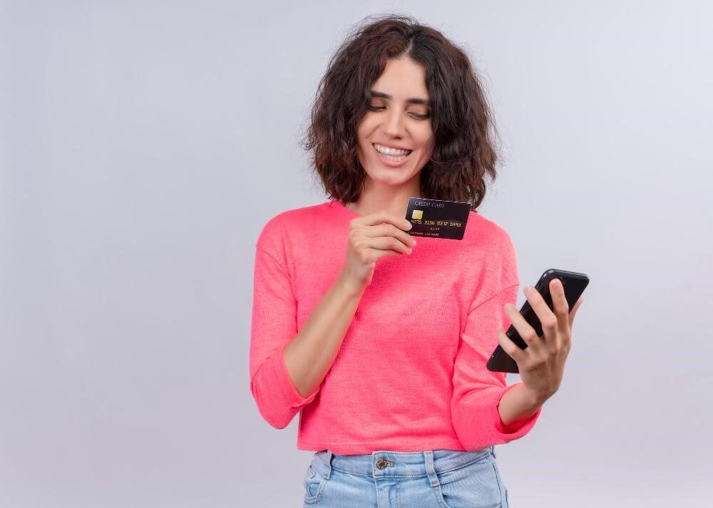 زن جوان در حال خرید اینترنتی با کارت بانکی و موبایل