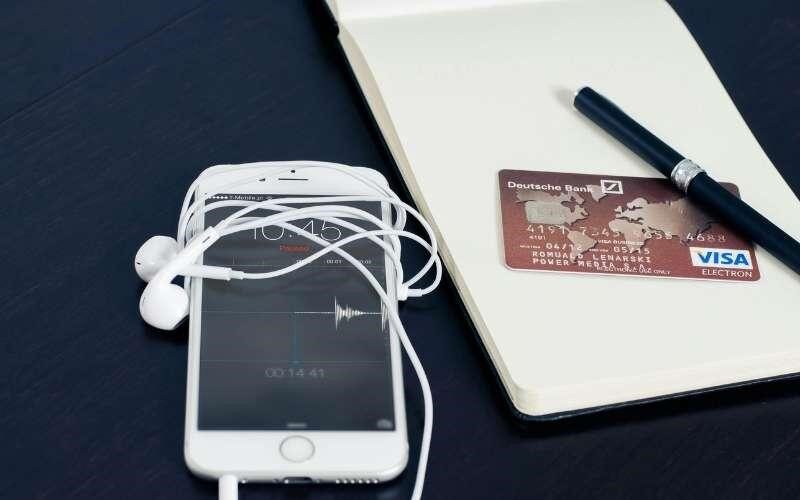 ویزا کارت فیزیکی کنار موبایل و دفترچه